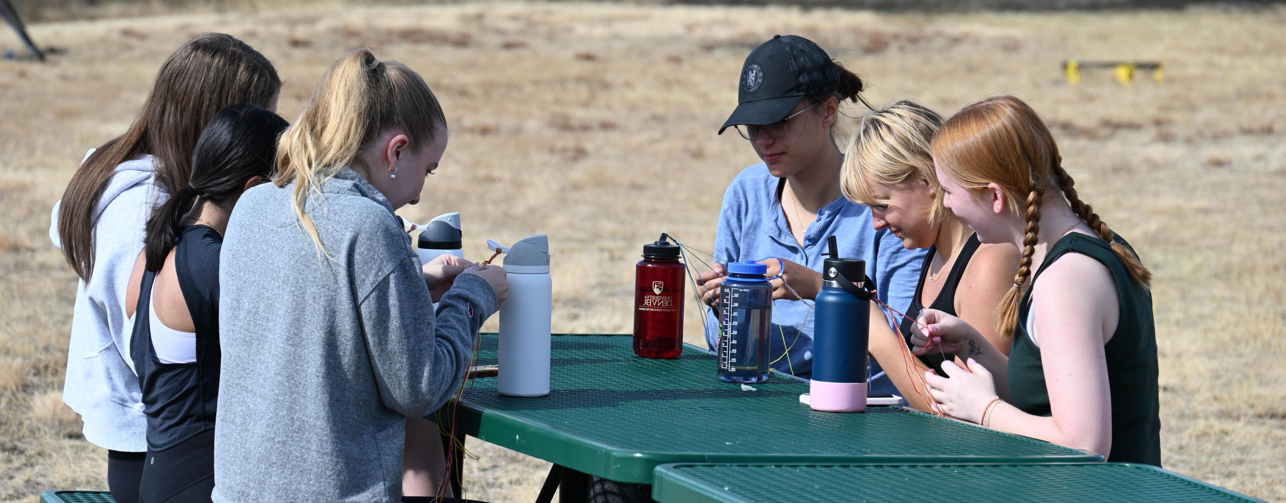 students gathered at picnic table in the meadow