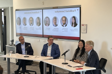 Four panelists sitting at two tables talking to audience about AI 